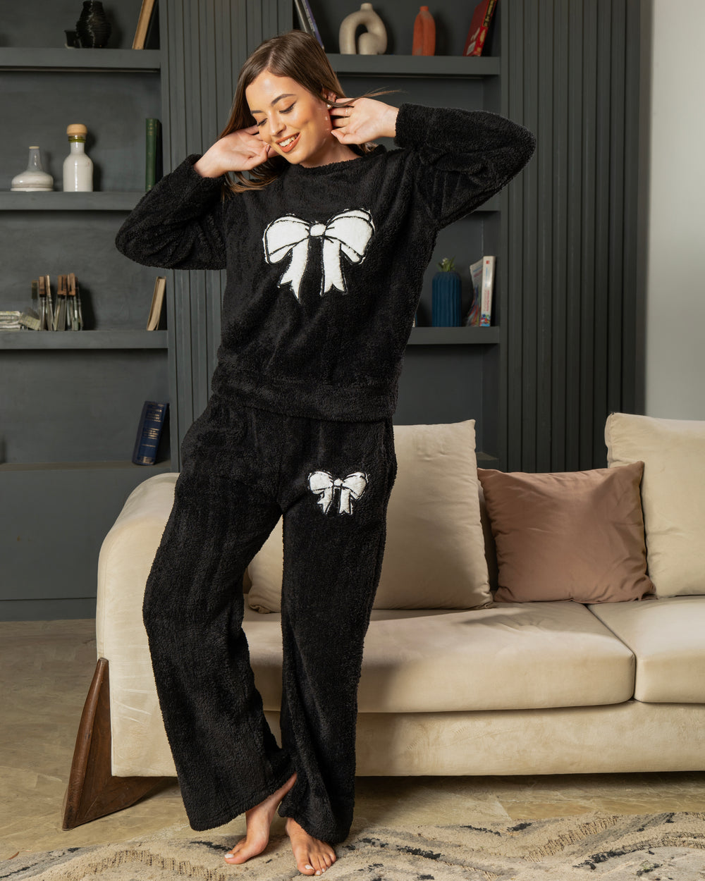 طقم بيجامة Noir Bow من PYJAMODA باللون الأسود، خامة فرو ناعمة وفيونكة بيضاء مع بنطلون Wide Leg واسع.
 
