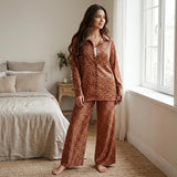 موديل ترتدى بيجامة ستان تايجر واقفة داخل غرفة نوم بإضاءة طبيعية مع بنطلون واسع وقميص بأزرار