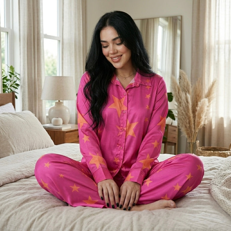 موديل جالسة على السرير ترتدى بيجامة ستان بطبعة نجوم مع إطلالة مريحة وأنيقة