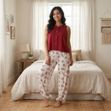 موديل ترتدى بيجامة قطن مكونة من تيشيرت أحمر بدون أكمام وبنطلون مطبوع جالسة فى غرفة نوم بإضاءة طبيعية