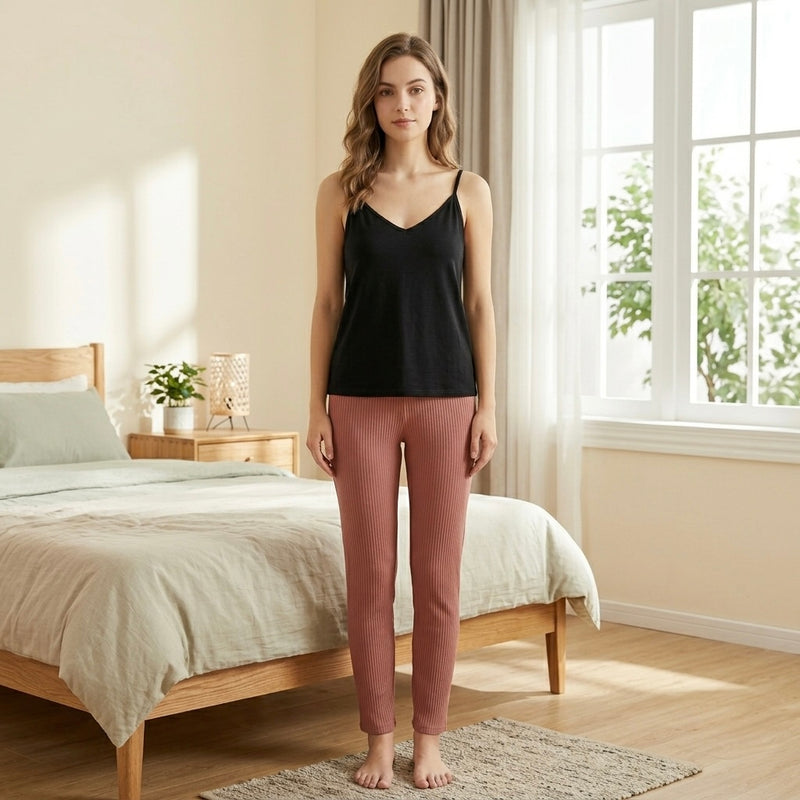 موديل واقفة تعرض بيجامة قطن مريحة مكونة من تيشيرت حمالات أسود وبنطلون ريب مضلع كامل