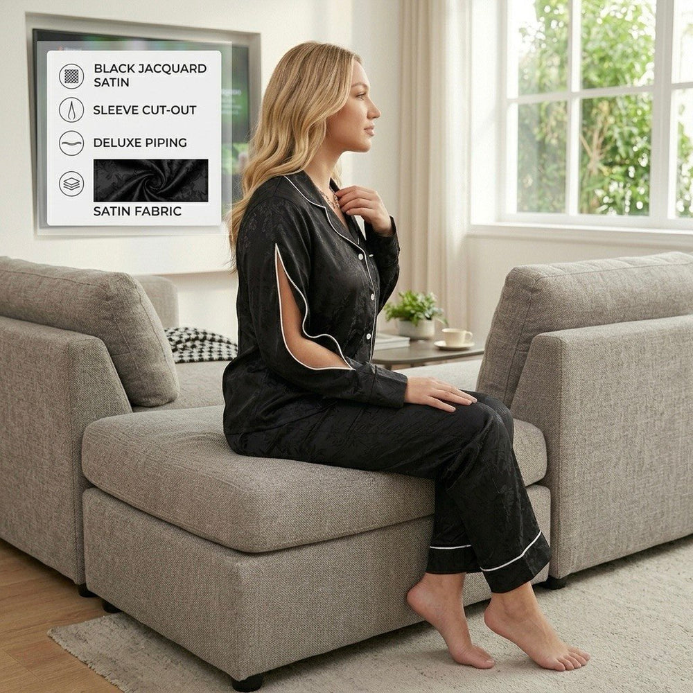 موديل جالسة ترتدي بيجامة ستان سوداء فاخرة بتصميم بزراير وأكمام مفتوحة