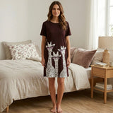 Woman wearing a brown dress with giraffe design in a bedroom.